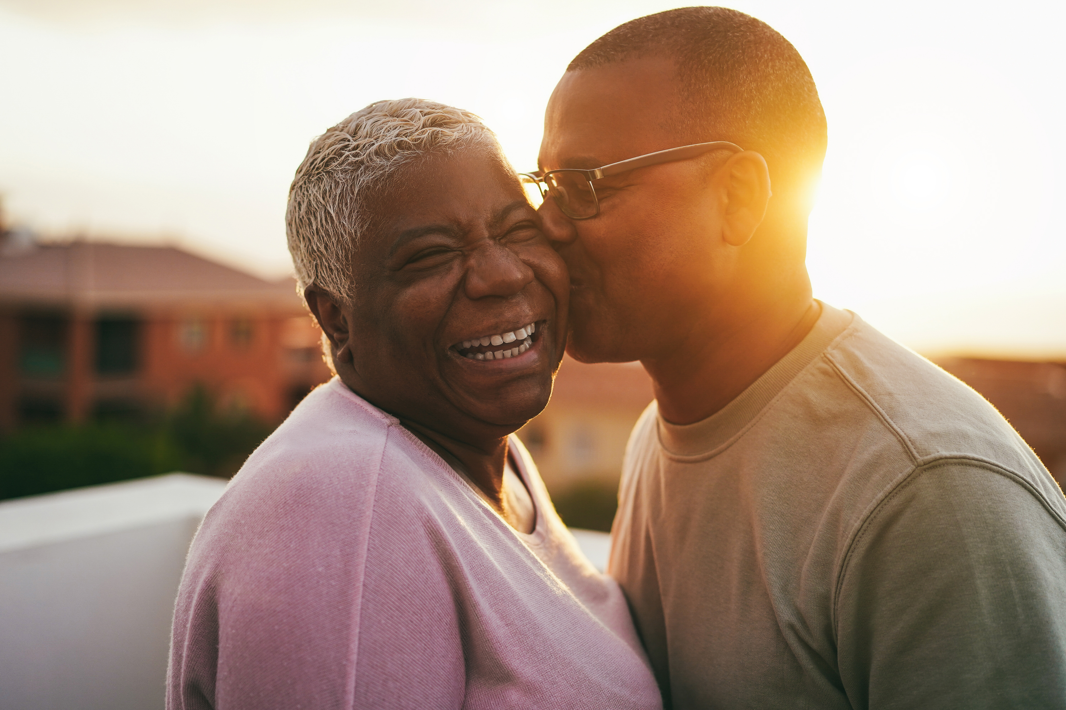 Happy african senior couple having tender moment outdoors at sunset time - Focus on woman face